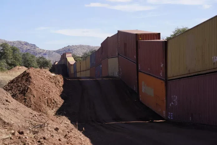 A long row of double-stacked shipping contrainers provide a new wall between the United States and Mexico in the remote section area of San Rafael Valley, Ariz., Thursday, Dec. 8, 2022. Work crews are steadily erecting hundreds of double-stacked shipping containers along the rugged east end of Arizona’s boundary with Mexico as Republican Gov. Doug Ducey makes a bold show of border enforcement even as he prepares to step aside next month for Democratic Governor-elect Katie Hobbs. (AP Photo/Ross D. Franklin)